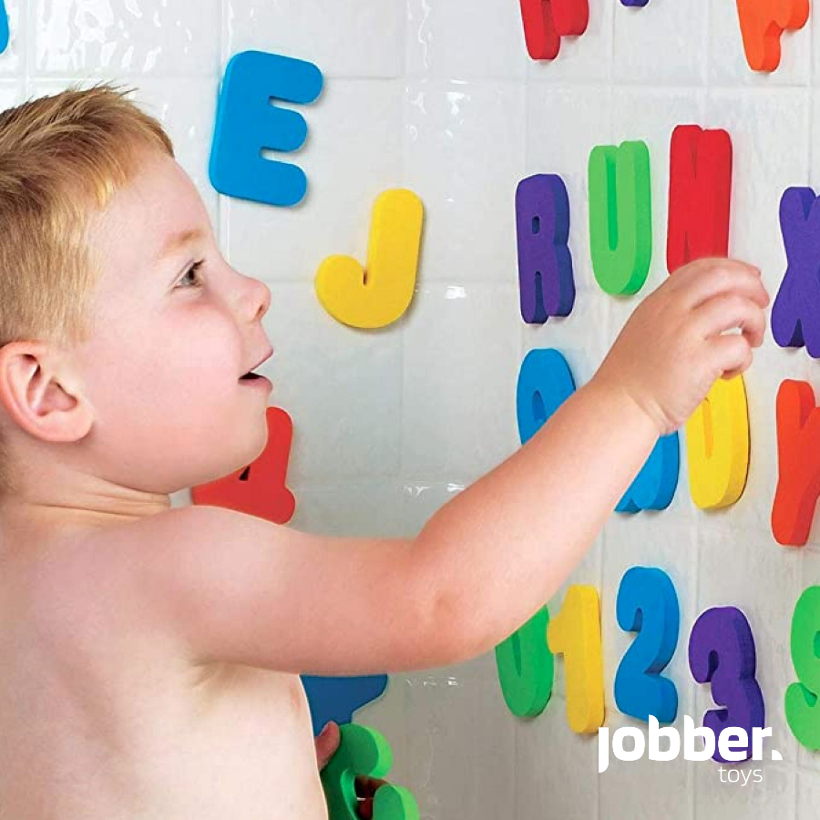 Kind speelt met natte foam letters tegen een tegelwand